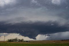 A dark, ominous severe thunderstorm with a dramatic lowering and wall cloud forming over the rural agricultural fields near Belleville, Kansas, on April 11, 2026. Extreme weather photography by storm chaser Mauro Greco